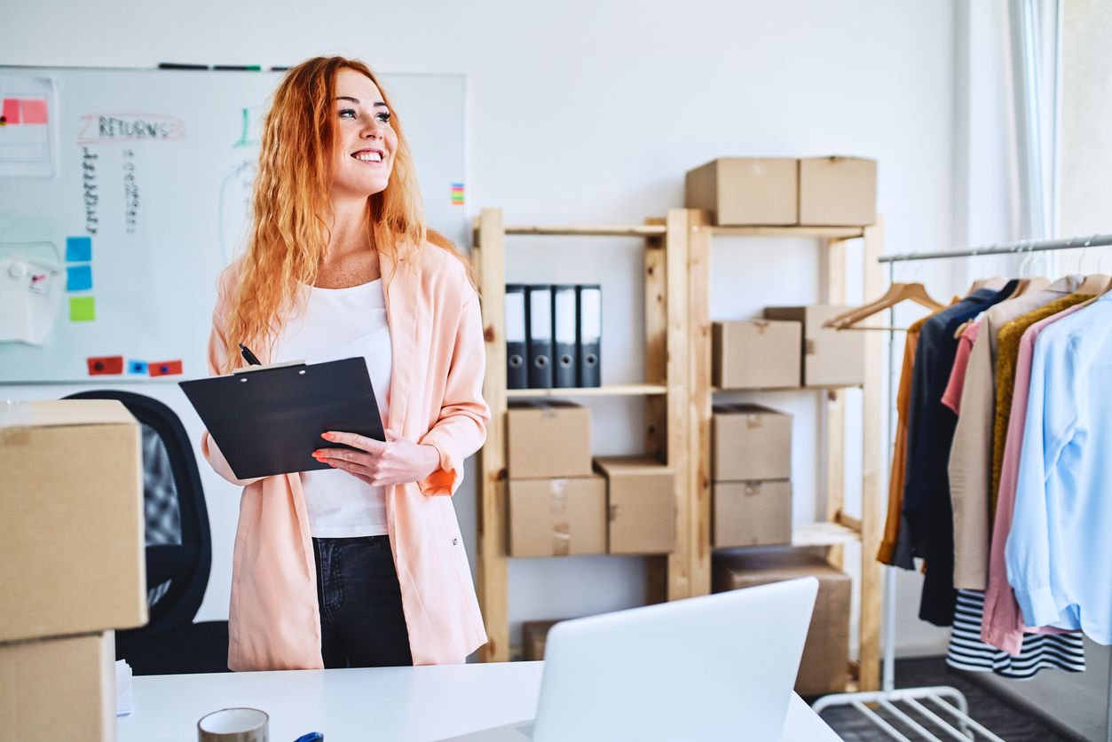 Small online clothing store owner proudly standing in office space and looking away