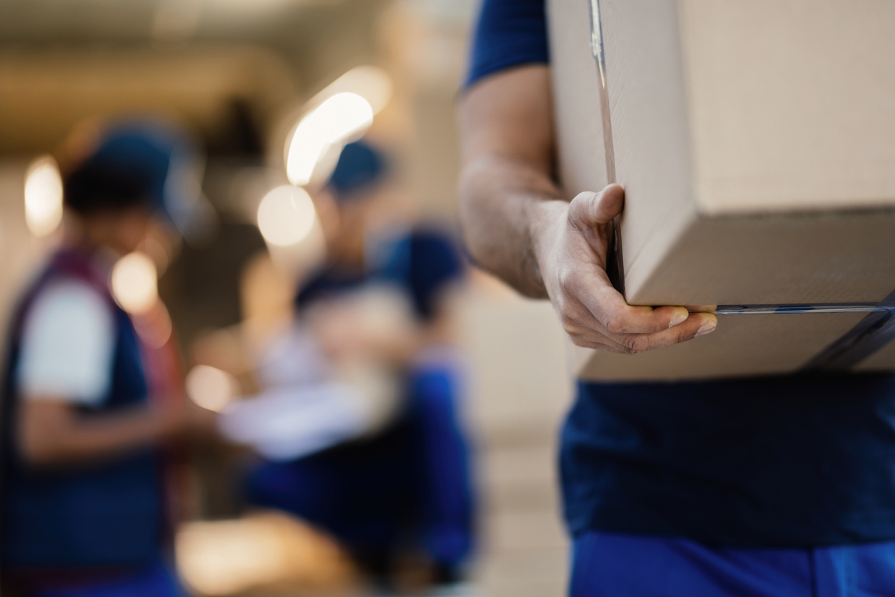 Close-up of a worker carrying cardboard box while making a delivery