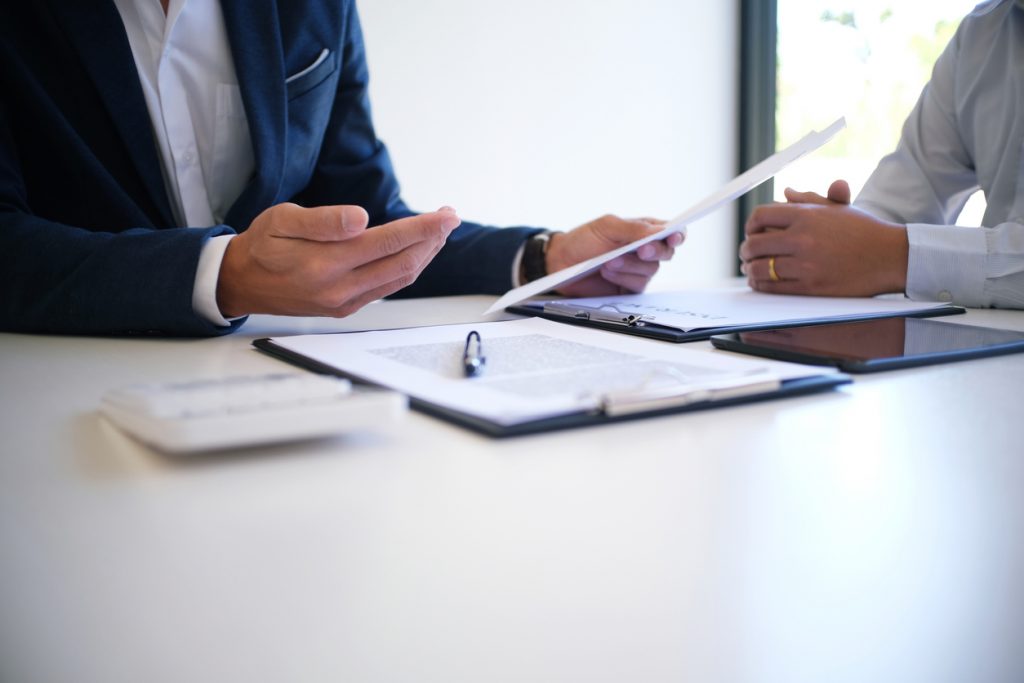 Sales manager giving advice application form document, considering mortgage loan offer for car and house insurance.