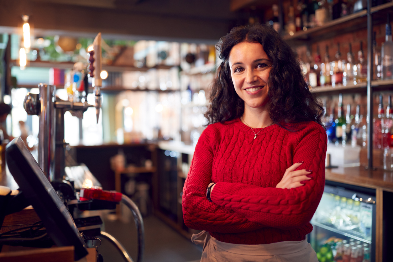Portrait Of Smiling Female Bar Owner Standing Behind Counter
